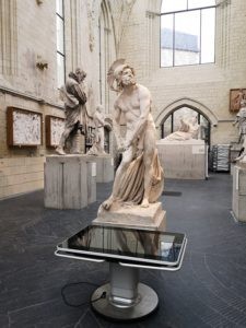 Table Kara devant une statue au musée